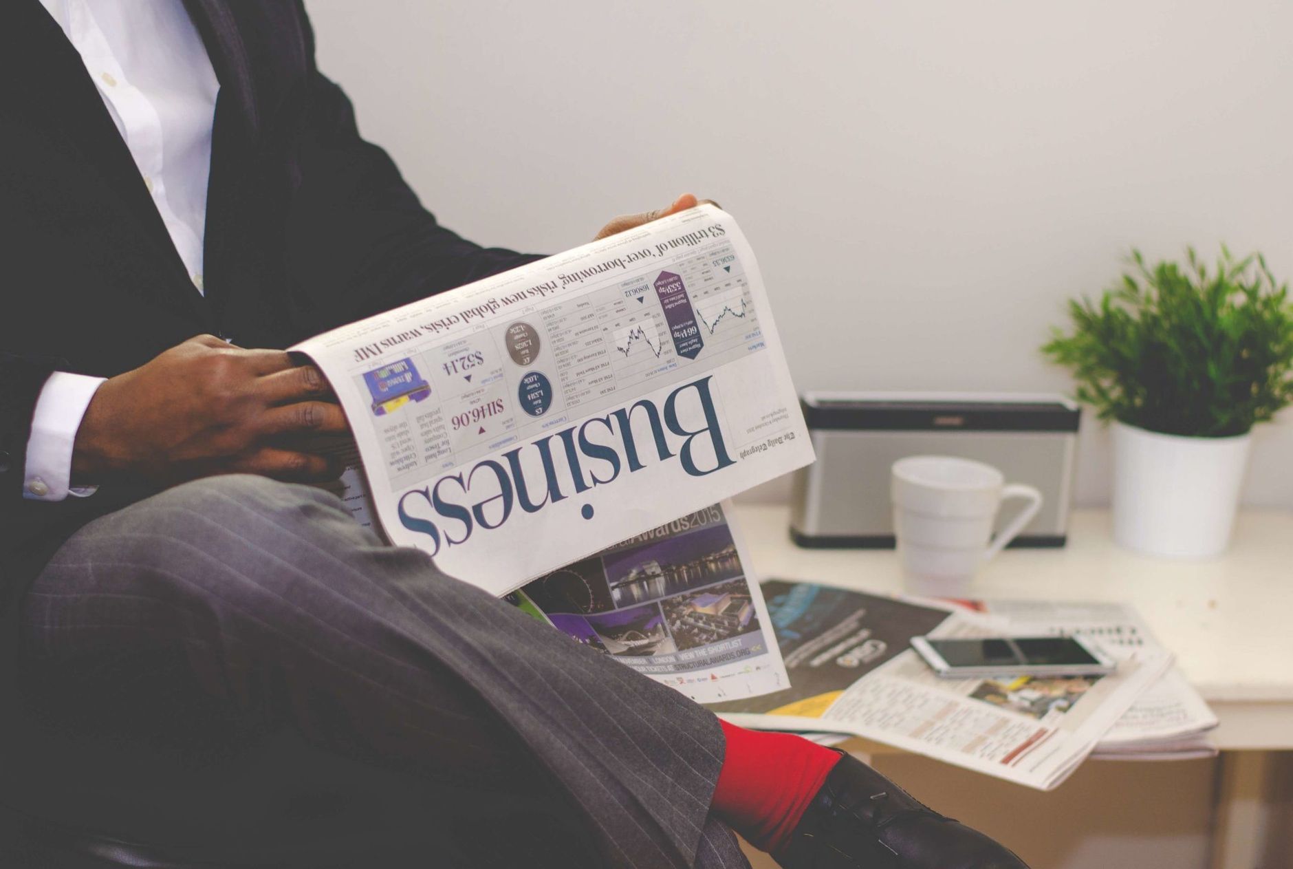 Businessman reading a financial newspaper at a desk, highlighting finance and commerce theme. — Breaking Barriers: Dr. Stephe