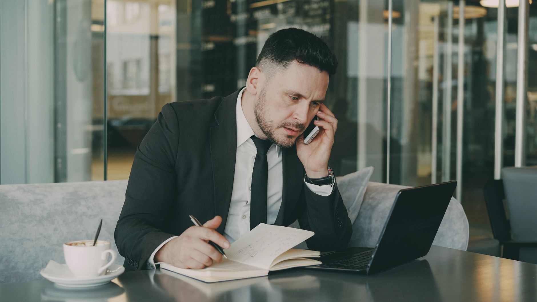 Businessman talks on phone while writing notes in a modern cafe. — From First-Time Buyers to Regulars: Choosing the Right Onl